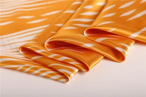 Close-up of orange silk satin scarf with white abstract stripes and glossy texture