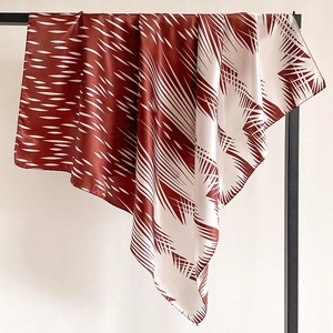 Detailed view of satin square scarf with modern geometric pattern in deep red and white