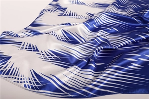 Detailed view of satin silk scarf with navy ink-style geometric patterns and hemmed edges