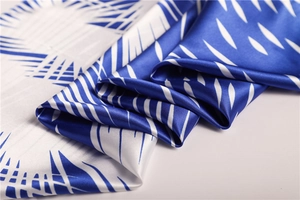 Detail of blue and white geometric satin scarf showing smooth silk texture and drape