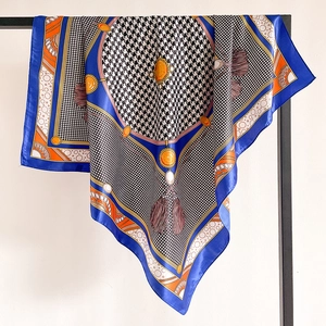 Detail view of houndstooth silk scarf with royal blue border and orange fringe patterns