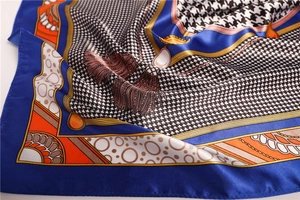 Detail of houndstooth silk scarf with chain and tassel patterns in blue and orange