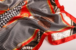 Macro detail showing houndstooth print and gold chain motifs on silky satin square scarf