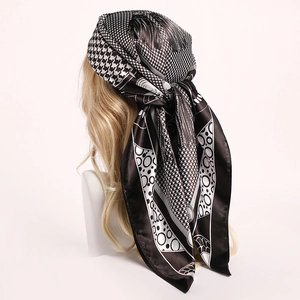 Classic black and white houndstooth silk scarf tied on a model head as a stylish headwrap