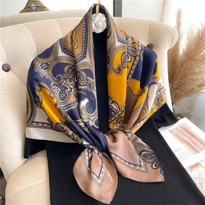Macro detail of navy and yellow paisley silk square scarf on a black knit dress