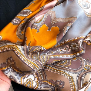 Detail of silk-like paisley pattern scarf with elegant orange and brown floral prints