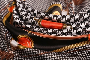 Detail of satin silk scarf featuring houndstooth pattern and luxury chain print design