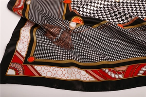 Detailed view of satin scarf with houndstooth pattern, gold chains, and red gemstones