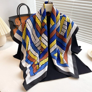 Close-up of square silk scarf featuring a geometric weave pattern in blue and yellow