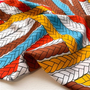 Detail of silk scarf showing multi-color rope pattern print and smooth satin texture