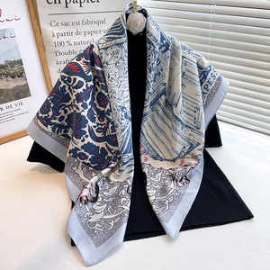 Detail of floral printed silk scarf elegantly draped over a black mock neck top