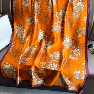 Elegant floral silk scarf in bright orange with traditional patterns and contrast border