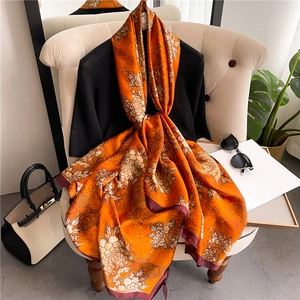 Detail of luxury orange floral silk scarf with chrysanthemum patterns and golden clouds