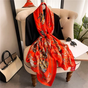 Luxury silk scarf with equestrian chain print in bright orange hanging on a rack