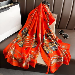 Luxurious orange silk scarf with baroque chain and crown prints in a stylish setup