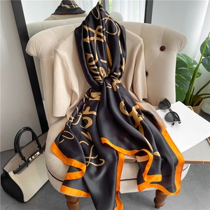 Detail of silk scarf with golden letters and orange borders draped on a chair
