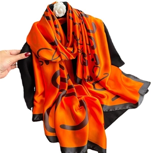 Luxurious orange silk scarf with H letter print and white camellia brooch detail