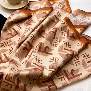 Gros plan du foulard en soie à motifs géométriques avec ourlet orange et texture lisse