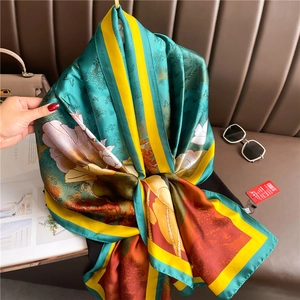 Detailed view of emerald silk scarf with floral patterns draped on a leather couch