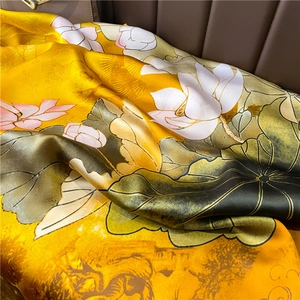 Detailed view of yellow silk scarf featuring lotus and landscape painting patterns