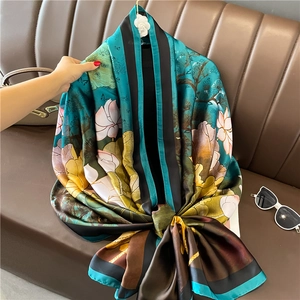 Detail of luxury silk scarf showing lotus and pine patterns on navy blue fabric