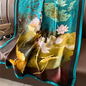 Detail view of a luxury lotus leaf silk scarf with elegant floral patterns on a leather sofa