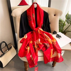 Detail of red silk shawl with lotus prints draped on a chair with accessories