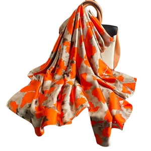 Luxurious large silk scarf with orange abstract ink pattern draped over a handbag