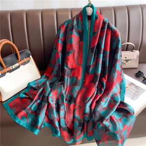 Detailed texture of gradient floral silk scarf draped elegantly on a leather sofa