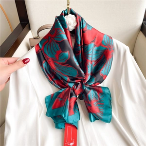 Detail of floral gradient silk scarf with vibrant red and green patterns on white shirt