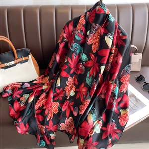 Detail of silk scarf with red and teal maple leaf patterns on a brown leather sofa