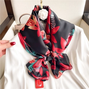 Detail of silk scarf with floral patterns draped over white blazer for elegant styling