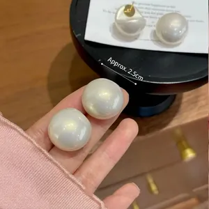Elegant 2.5cm large white faux pearl stud earrings with gold pins shown in hand