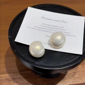 Elegant large round pearl stud earrings with mirror luster on a minimalist display card