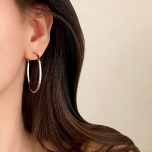 Elegant silver hoop earrings with vintage lattice texture on female model in side view