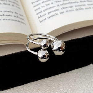 Detailed view of polished silver ball open rings displayed on black velvet display stand