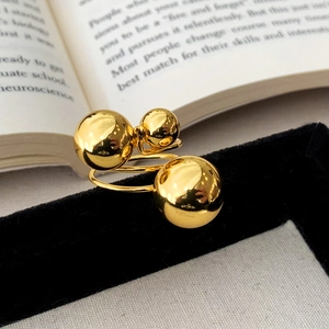 Macro view of modern gold triple ball ring on black velvet with vintage book background