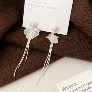 Détail de boucles d'oreilles pendantes élégantes avec perles et motifs floraux