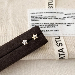Macro shot of minimalist star earrings with micro-inlaid cubic zirconia on a velvet display