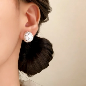 Exquisite silver stud earrings with zircon inlay and brushed hollow design on a model