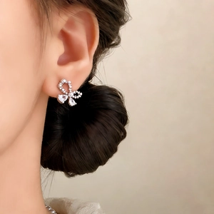 Elegant silver bow earrings with shiny cubic zirconia on model for a chic daily look