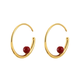 Boucles d'oreilles créoles dorées avec une perle rouge sur fond blanc pur