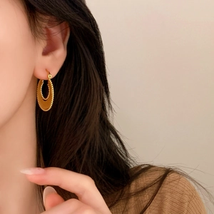 Minimalist gold hoop earrings with sunburst texture worn by a model in warm light