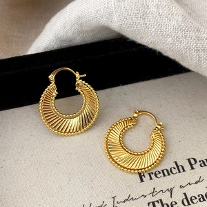 Macro detail of gold hoop earrings featuring sunburst facets and beaded trim texture