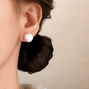 Minimalist large white pearl stud earrings with mirror luster on a model side profile