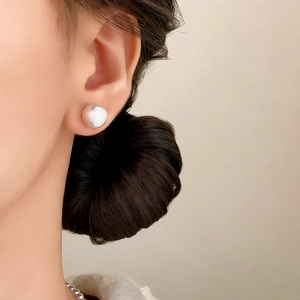 Elegant white pearl stud earring with brushed metal base worn by a model in a close-up view
