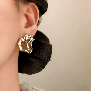 Irregular gold wave earrings with textured design shown on a model for a vintage style