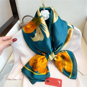 Détail d'un foulard en soie de luxe avec imprimés lys attaché à un pull blanc