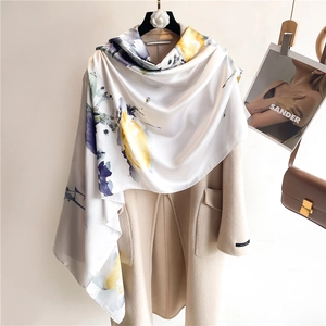 Dettaglio dello scialle in seta con motivi floreali a inchiostro su cappotto beige