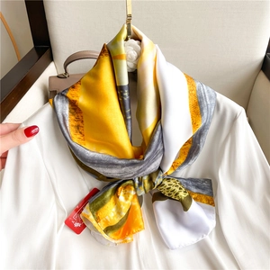 Dettaglio di un foulard in seta di lusso con motivi gialli e grigi su un blazer bianco